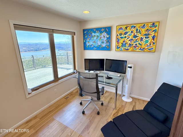 office featuring visible vents, a textured ceiling, baseboards, and wood finished floors