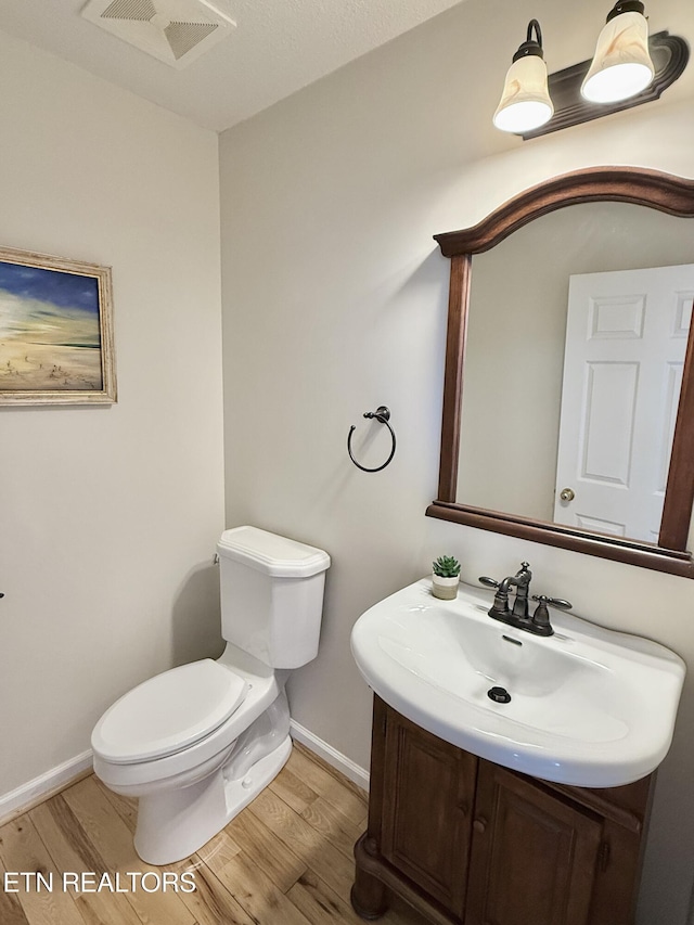 bathroom with visible vents, wood finished floors, toilet, and baseboards