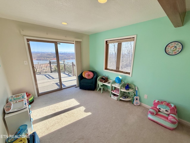 rec room featuring carpet floors, a water view, a textured ceiling, beamed ceiling, and baseboards