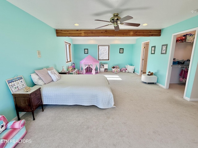 bedroom with baseboards, a ceiling fan, carpet, a spacious closet, and beam ceiling