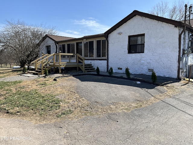 view of front of house with crawl space, a wooden deck, and a sunroom