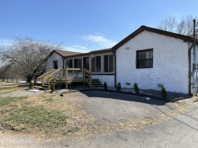 view of front of house with a sunroom, crawl space, a deck, and stucco siding