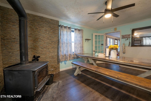 dining space featuring a wood stove, crown molding, a textured ceiling, and wood finished floors