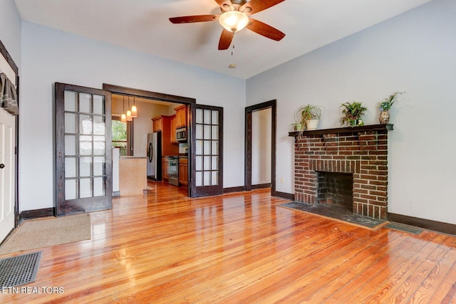 living room with light wood-style floors, a fireplace, visible vents, and baseboards