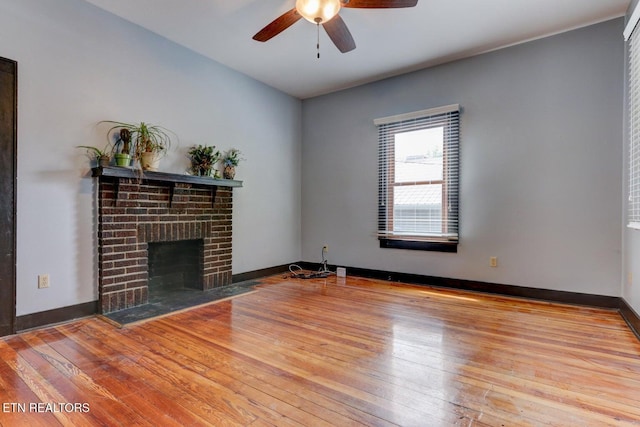 unfurnished living room featuring a fireplace, a ceiling fan, baseboards, and wood-type flooring