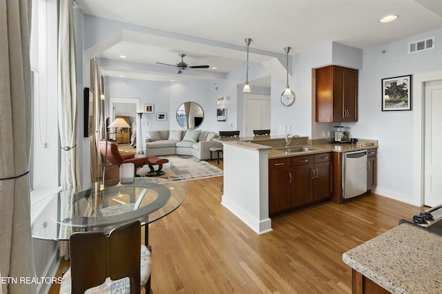 kitchen featuring light wood finished floors, visible vents, dishwasher, and a sink