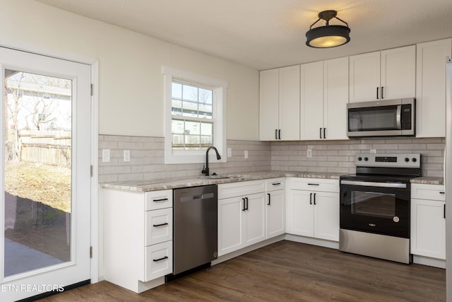 kitchen featuring stainless steel appliances, white cabinets, a sink, and dark wood-style floors