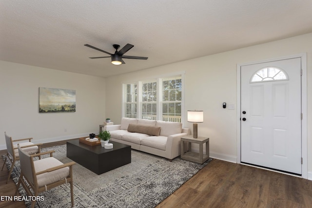 living area featuring dark wood finished floors, a textured ceiling, baseboards, and ceiling fan