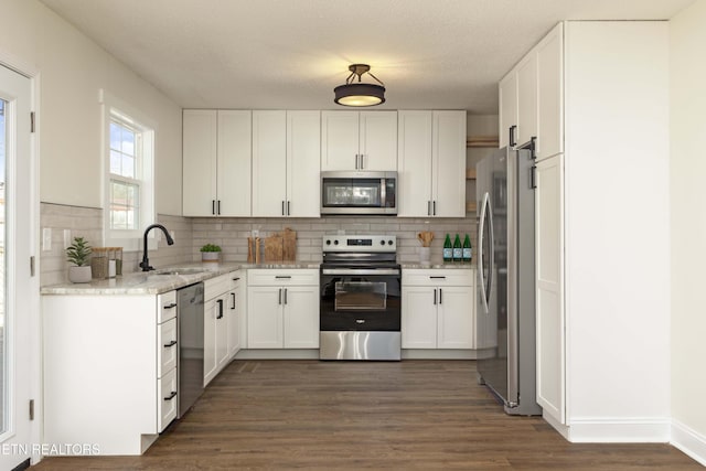 kitchen featuring appliances with stainless steel finishes, white cabinets, and a sink