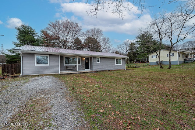 ranch-style house featuring a front yard, gravel driveway, covered porch, and metal roof