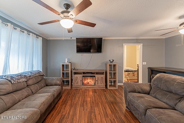 living room featuring dark wood finished floors, ceiling fan, a lit fireplace, a textured ceiling, and crown molding