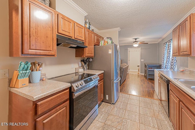 kitchen with brown cabinets, crown molding, appliances with stainless steel finishes, ceiling fan, and under cabinet range hood