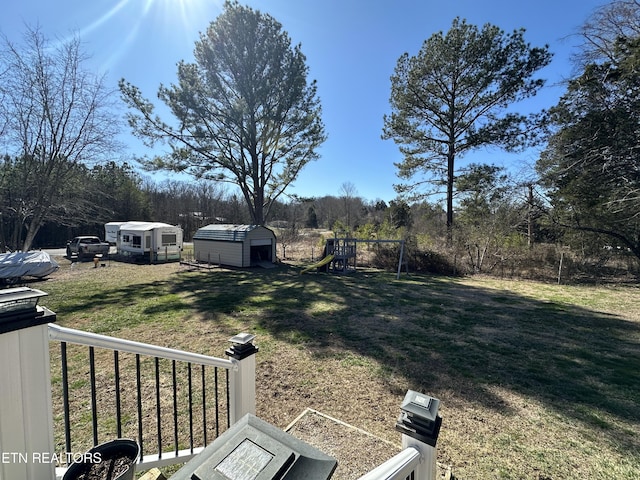 view of yard featuring a storage unit, a playground, and an outbuilding