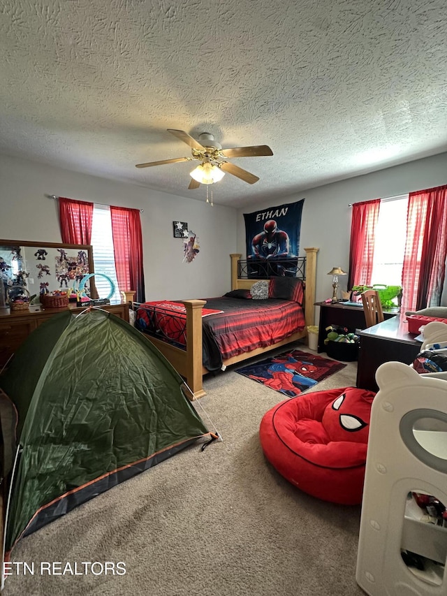 bedroom featuring carpet floors, a textured ceiling, and a ceiling fan