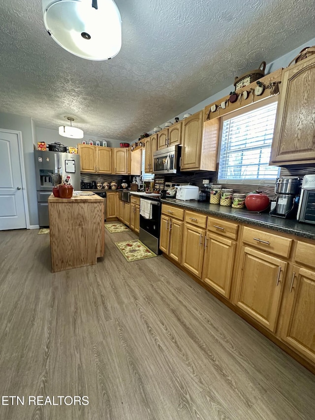 kitchen featuring dark countertops, light wood finished floors, appliances with stainless steel finishes, and a center island