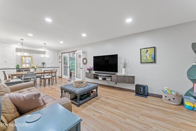 living area featuring light wood-style flooring, baseboards, a chandelier, and recessed lighting