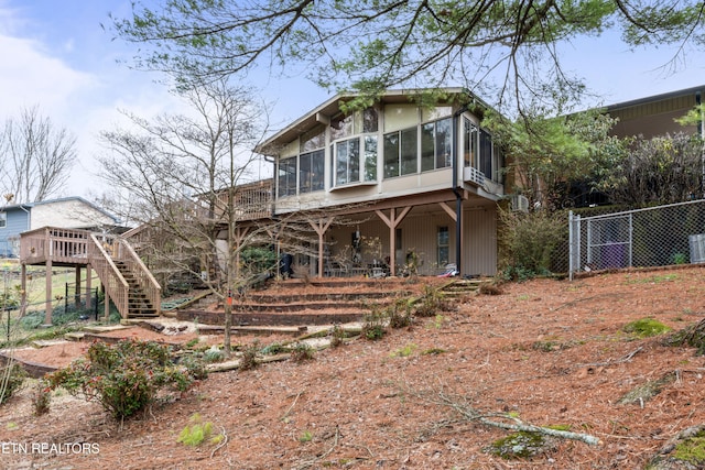 view of front of home featuring a sunroom, fence, stairway, and a deck