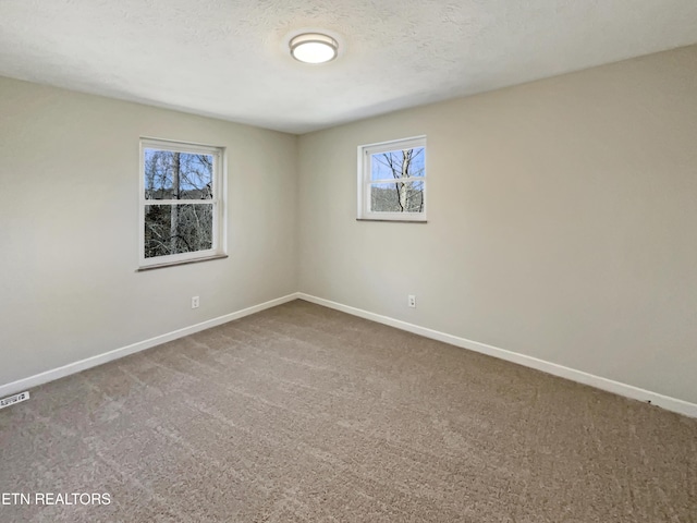 empty room featuring a textured ceiling, carpet floors, and baseboards