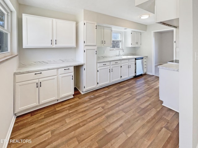 kitchen with light stone counters, a sink, light wood-style floors, white cabinets, and stainless steel dishwasher