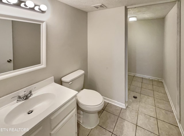 bathroom with a textured ceiling, toilet, vanity, visible vents, and tile patterned floors