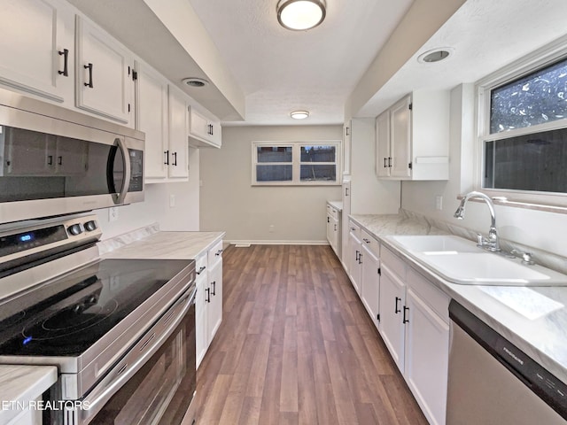 kitchen featuring white cabinets, dark wood-style flooring, stainless steel appliances, and a sink