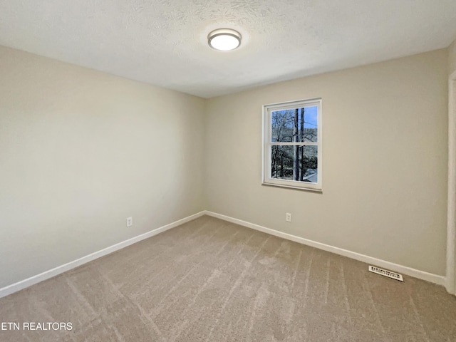 spare room with a textured ceiling, carpet floors, visible vents, and baseboards