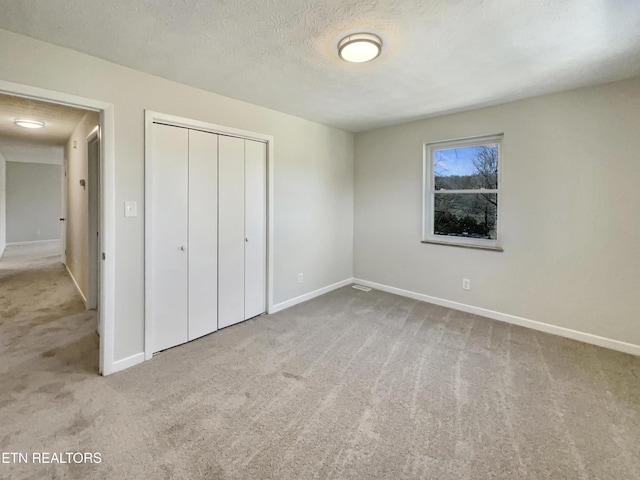 unfurnished bedroom featuring a closet, carpet flooring, a textured ceiling, and baseboards