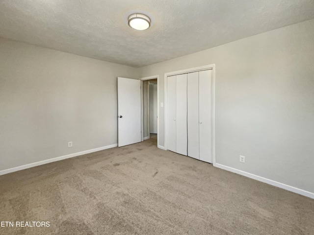 unfurnished bedroom with carpet floors, a closet, baseboards, and a textured ceiling