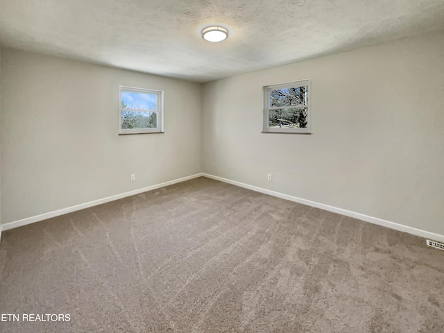 carpeted empty room featuring baseboards and a textured ceiling