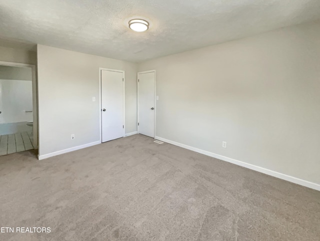 unfurnished bedroom featuring carpet, connected bathroom, baseboards, and a textured ceiling