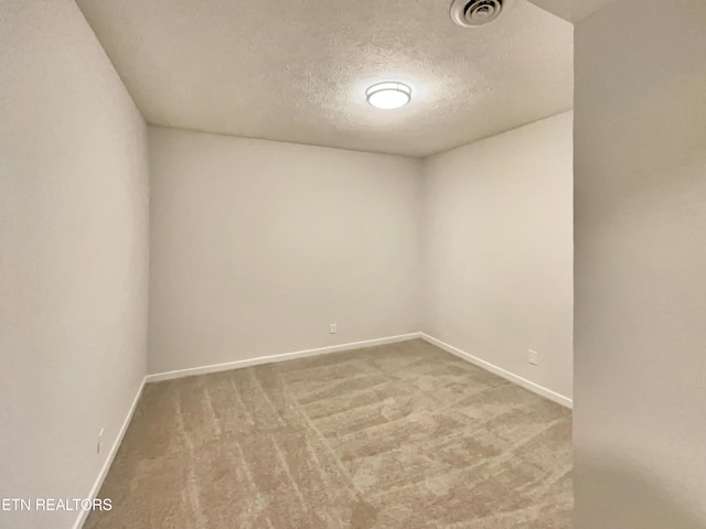 carpeted spare room with visible vents, a textured ceiling, and baseboards