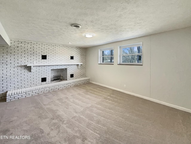 unfurnished living room featuring visible vents, baseboards, carpet, a textured ceiling, and a fireplace