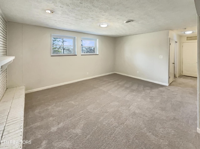 empty room with carpet, visible vents, a textured ceiling, and baseboards