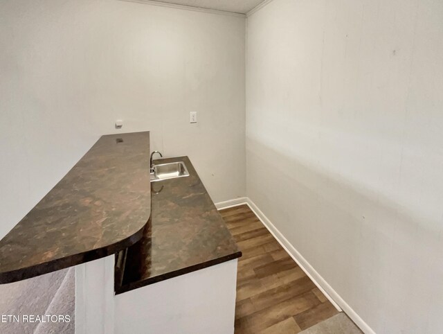 laundry area featuring crown molding, wood finished floors, a sink, and baseboards