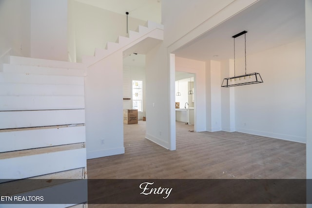 interior space with a high ceiling, baseboards, and wood finished floors