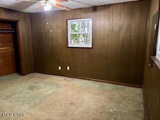 unfurnished bedroom featuring ceiling fan and wood walls