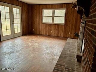 interior space with plenty of natural light, french doors, and wood walls