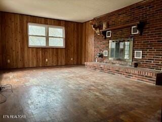 unfurnished living room with wood walls and a fireplace