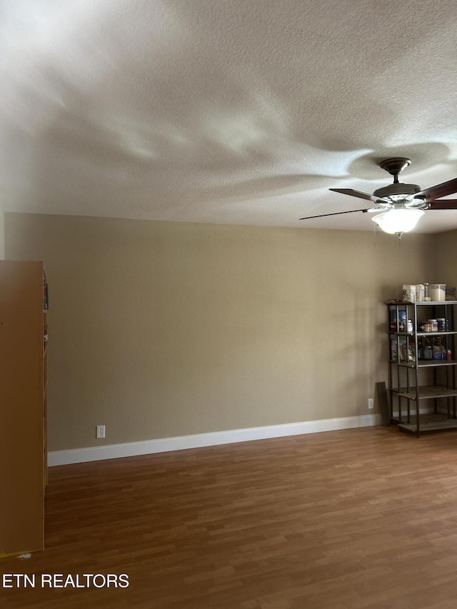 spare room with baseboards, a ceiling fan, wood finished floors, and a textured ceiling
