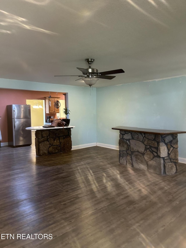 living area with baseboards, ceiling fan, and dark wood-style floors