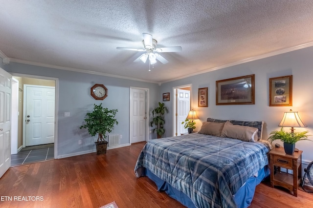 bedroom featuring visible vents, crown molding, a textured ceiling, and wood finished floors