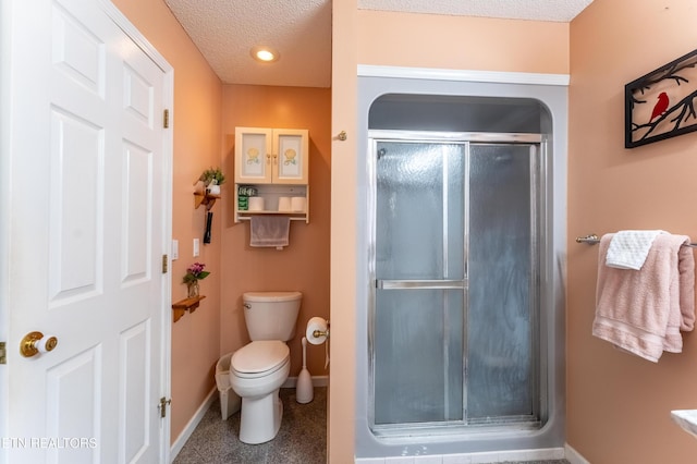 full bath with a textured ceiling, a stall shower, toilet, and baseboards