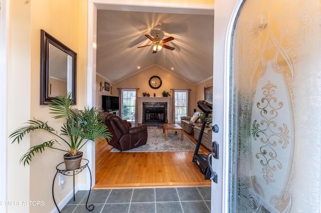 living area featuring vaulted ceiling, ceiling fan, dark tile patterned floors, and a fireplace