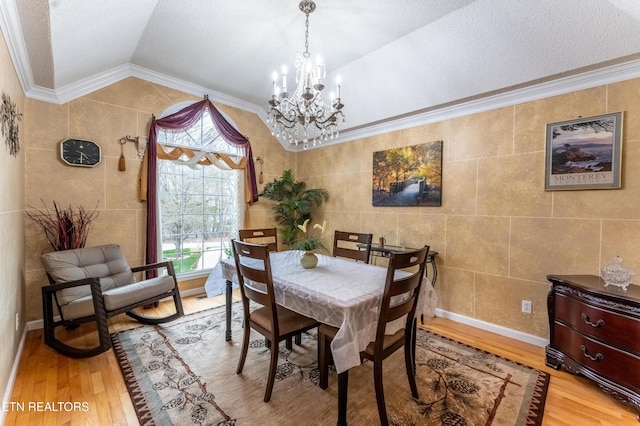 dining area with crown molding, tile walls, light wood finished floors, lofted ceiling, and a chandelier