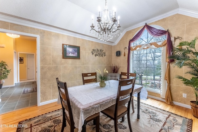 dining room with vaulted ceiling, wood finished floors, tile walls, and a notable chandelier