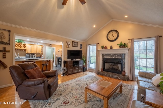 living room with light wood finished floors, ornamental molding, and vaulted ceiling