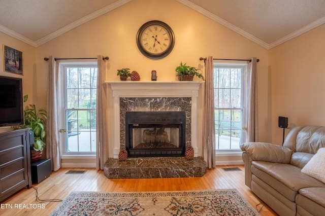 living area with lofted ceiling, a fireplace, wood finished floors, and crown molding