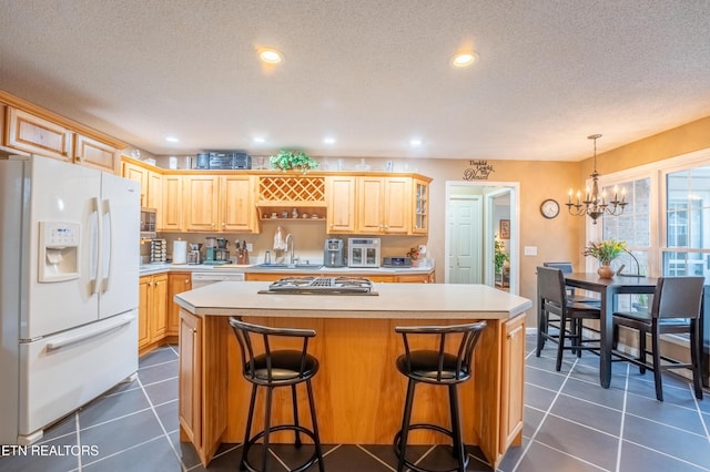 kitchen featuring white appliances, light countertops, a sink, and dark tile patterned floors