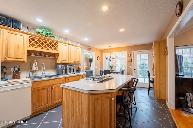 kitchen featuring dishwasher, a kitchen island, light countertops, gas stovetop, and a sink