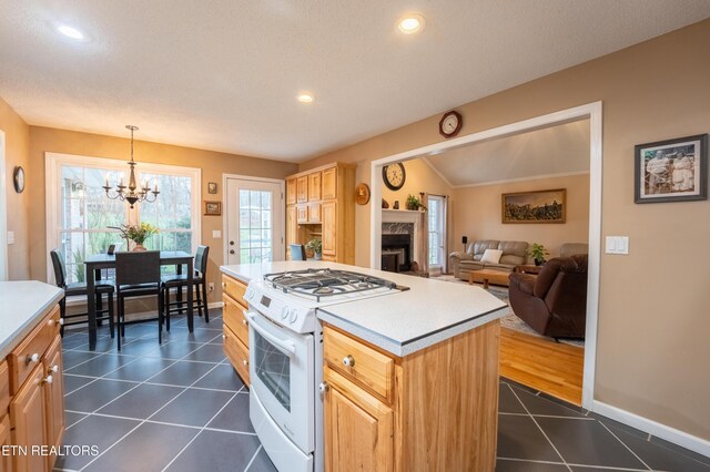 kitchen with dark tile patterned floors, a fireplace, light countertops, and white gas stove